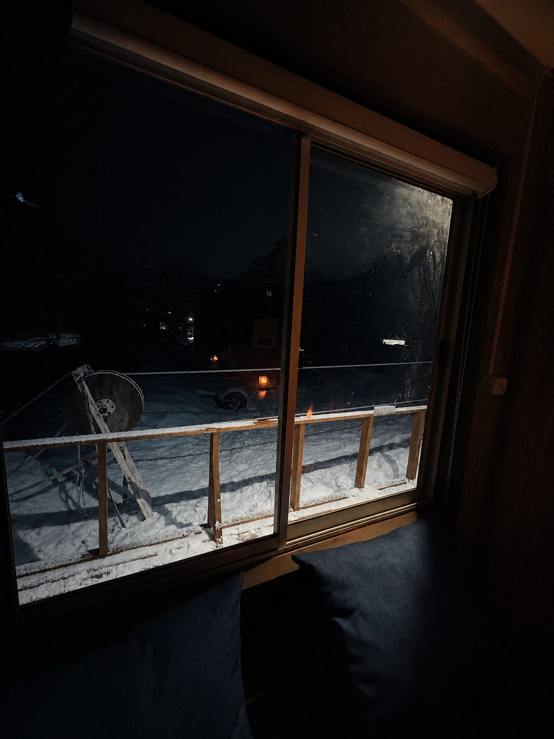 Vista nocturna del deck nevado desde el living